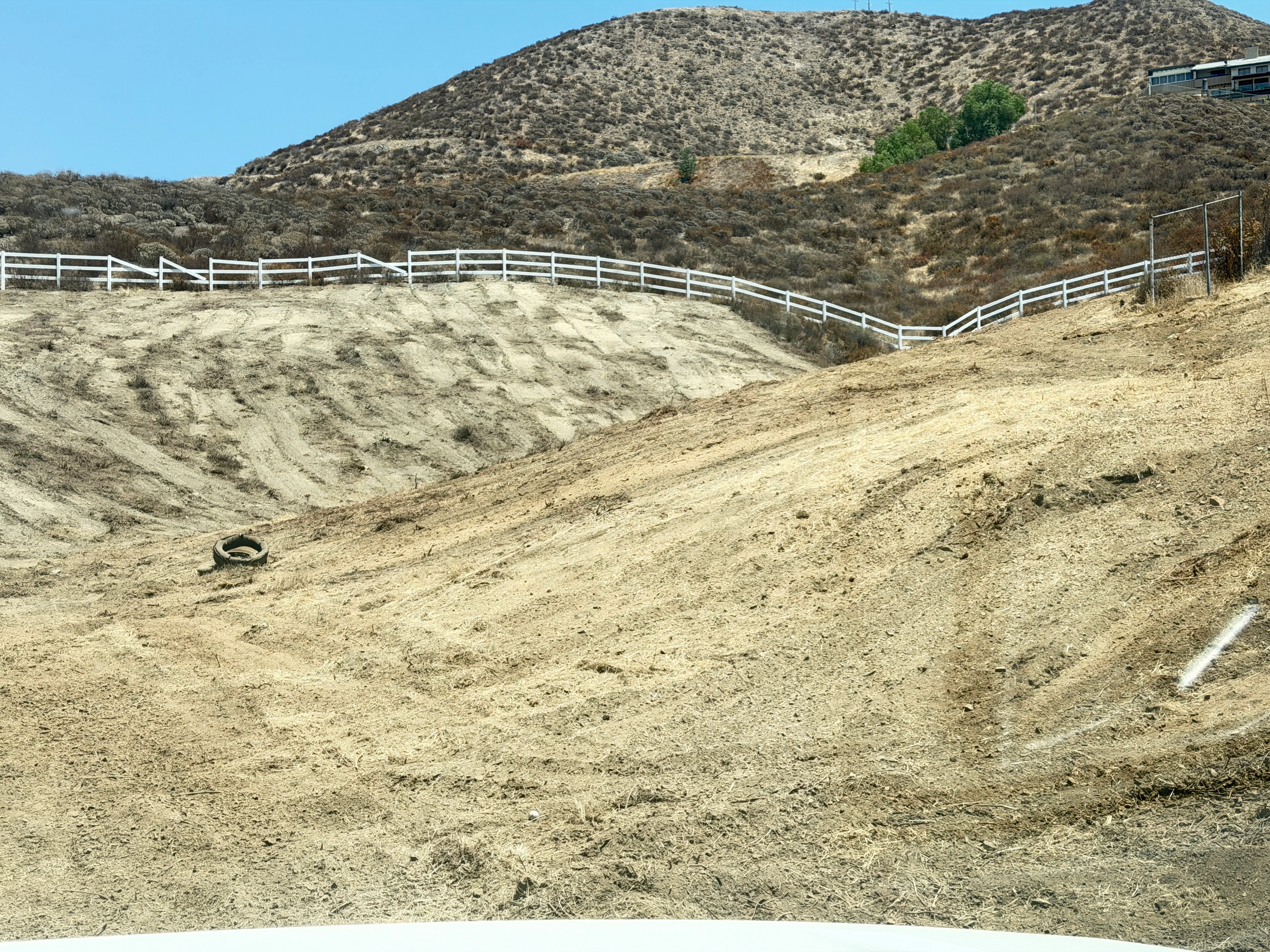 Cleared hillside with white ranch fencing and graded dirt slopes in Canyon Lake