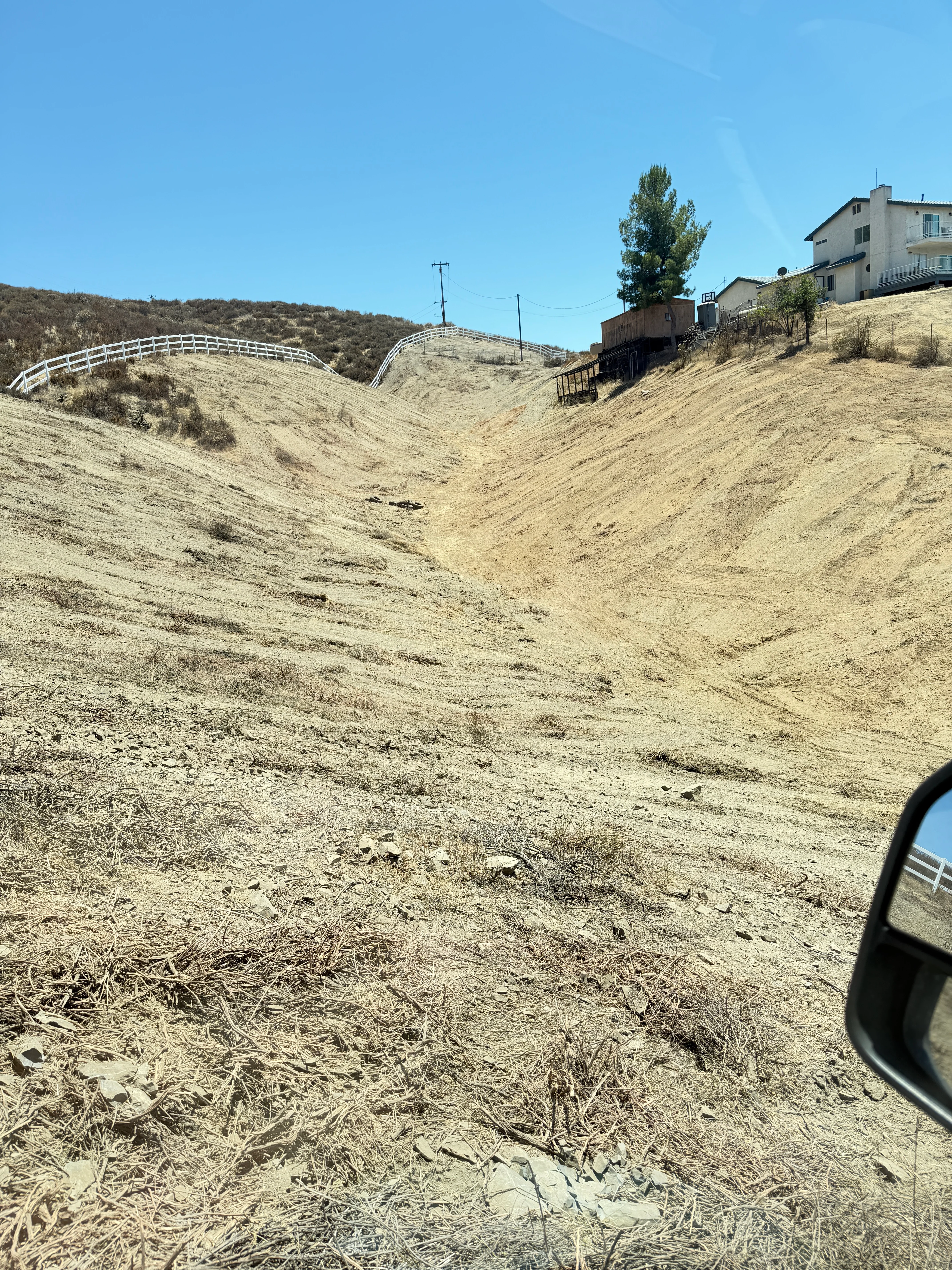 Cleared hillside with graded slopes and white fencing overlooking Canyon Lake property