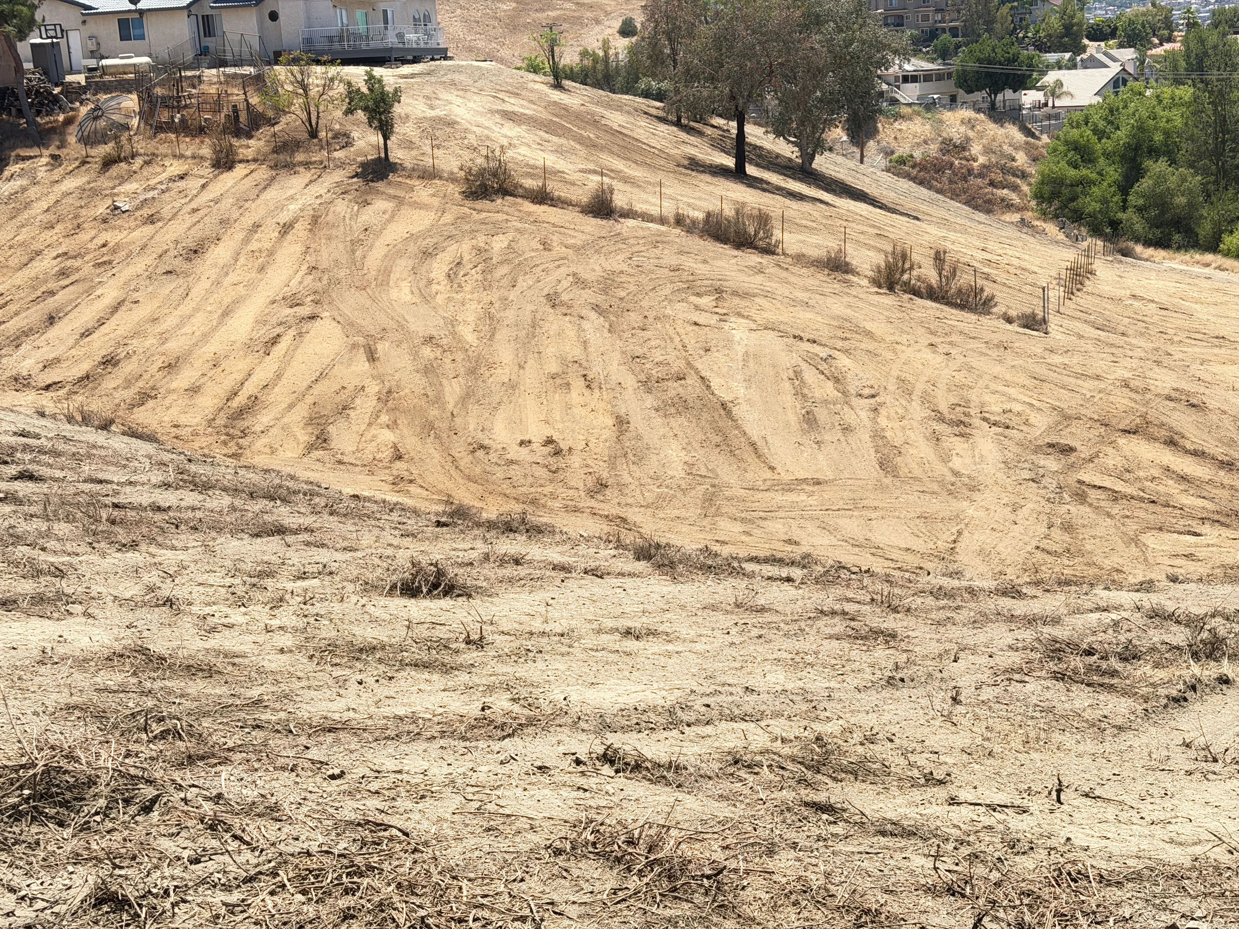 Cleared hillside with graded earth and erosion control fencing in Canyon Lake