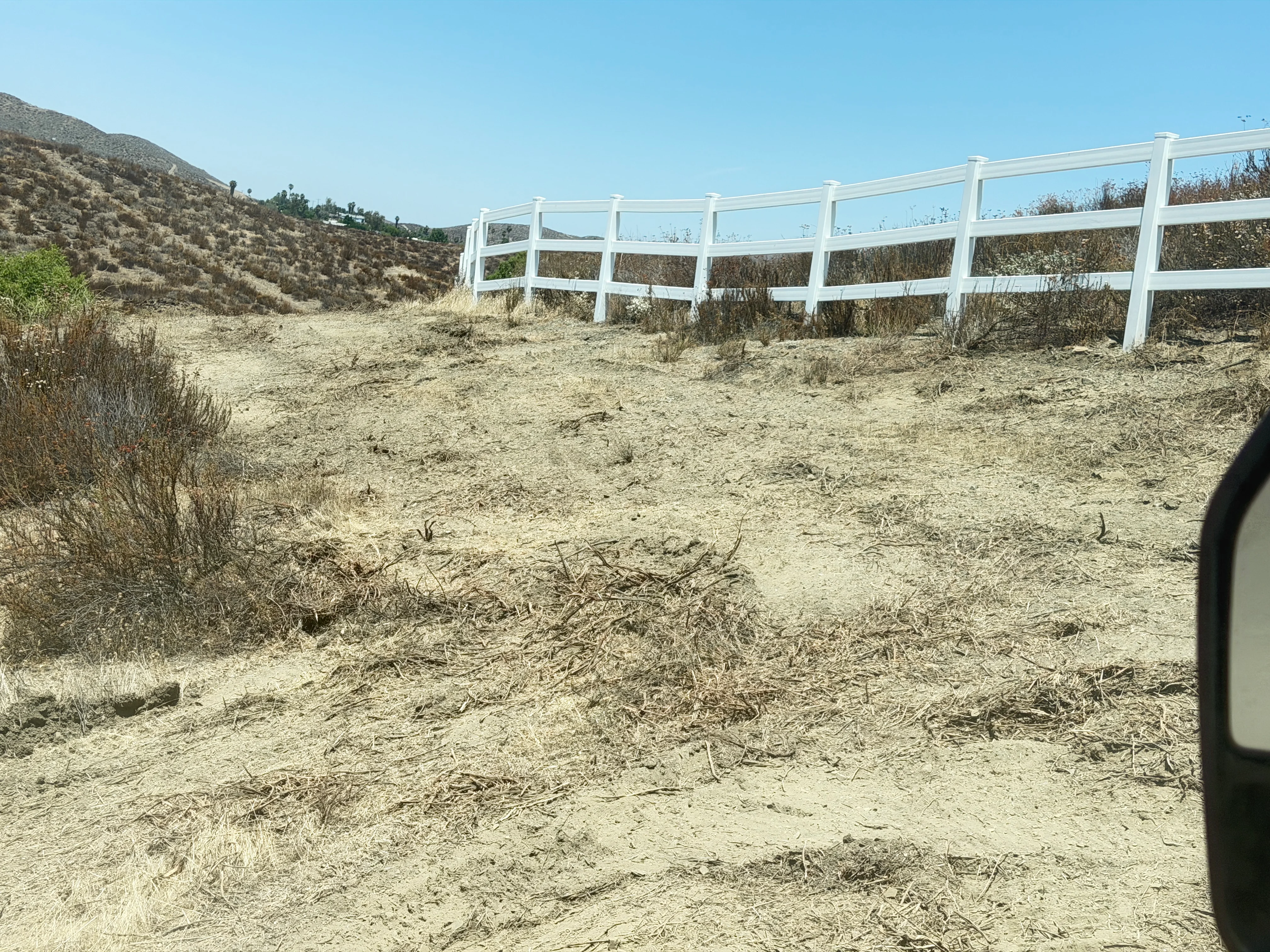 Cleared hillside with white ranch fencing installed along property line in Canyon Lake