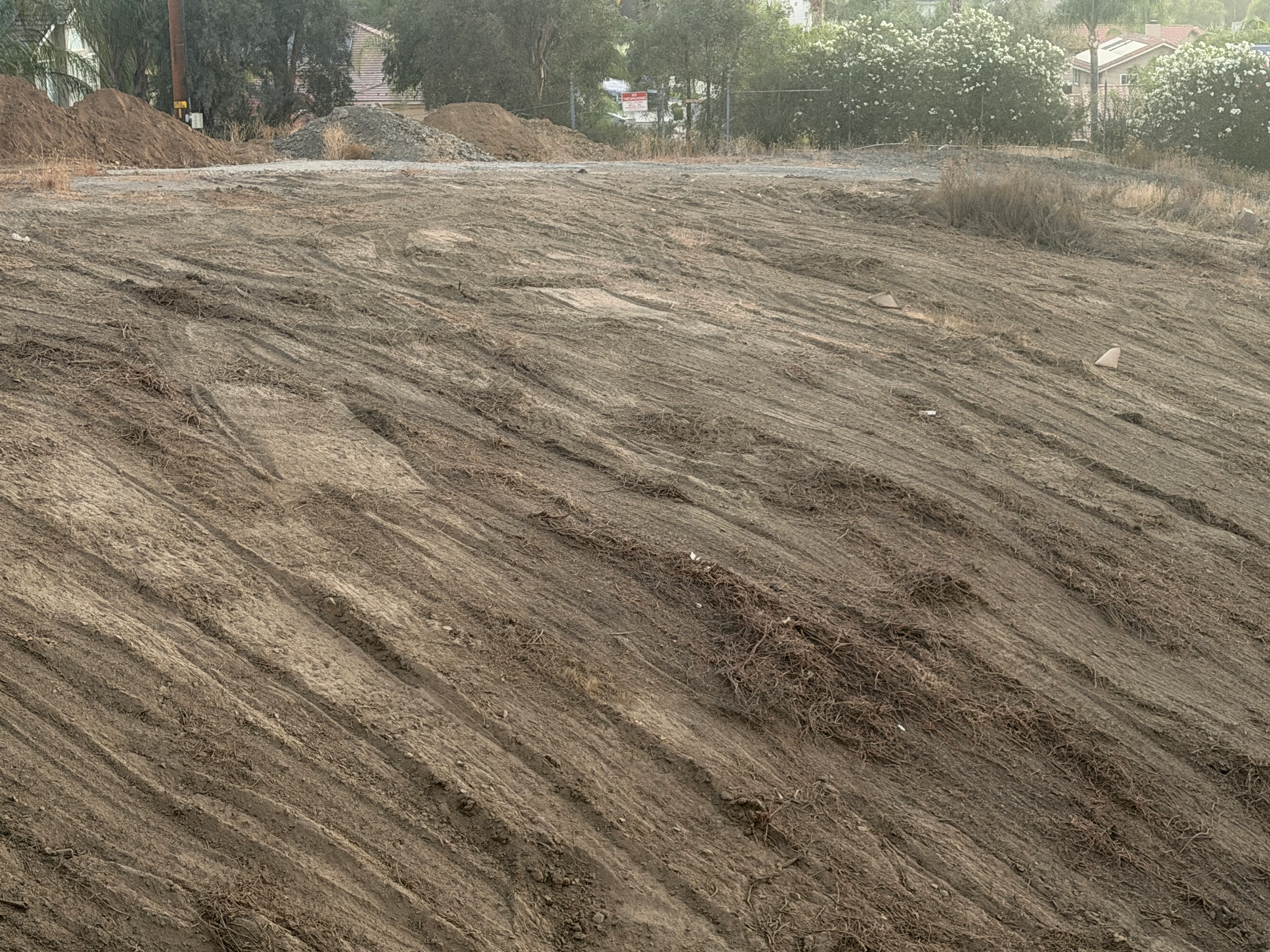 Cleared residential lot with graded dirt surface and material stockpiles in Canyon Lake