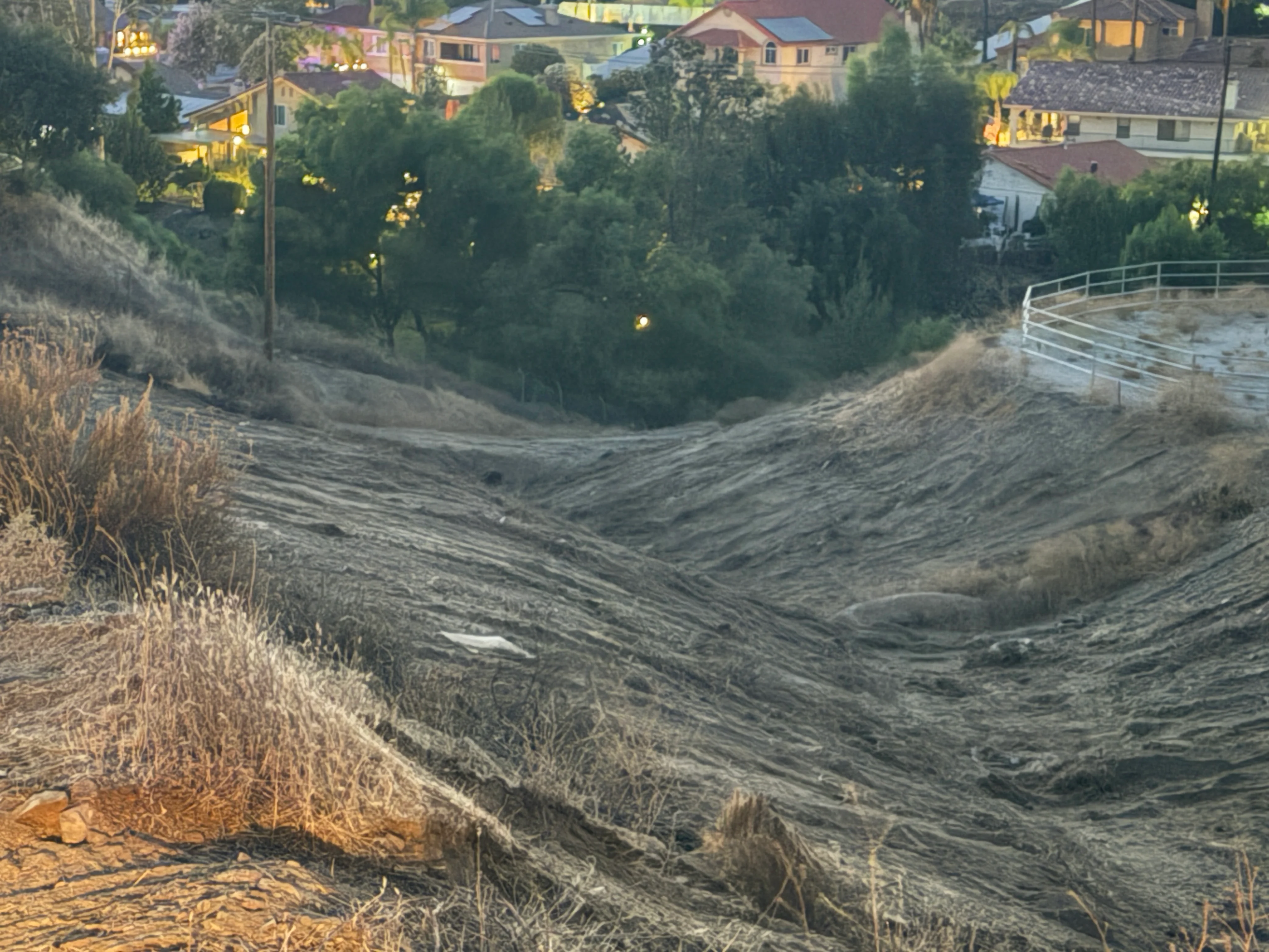 Cleared hillside with erosion control fencing overlooking Canyon Lake homes